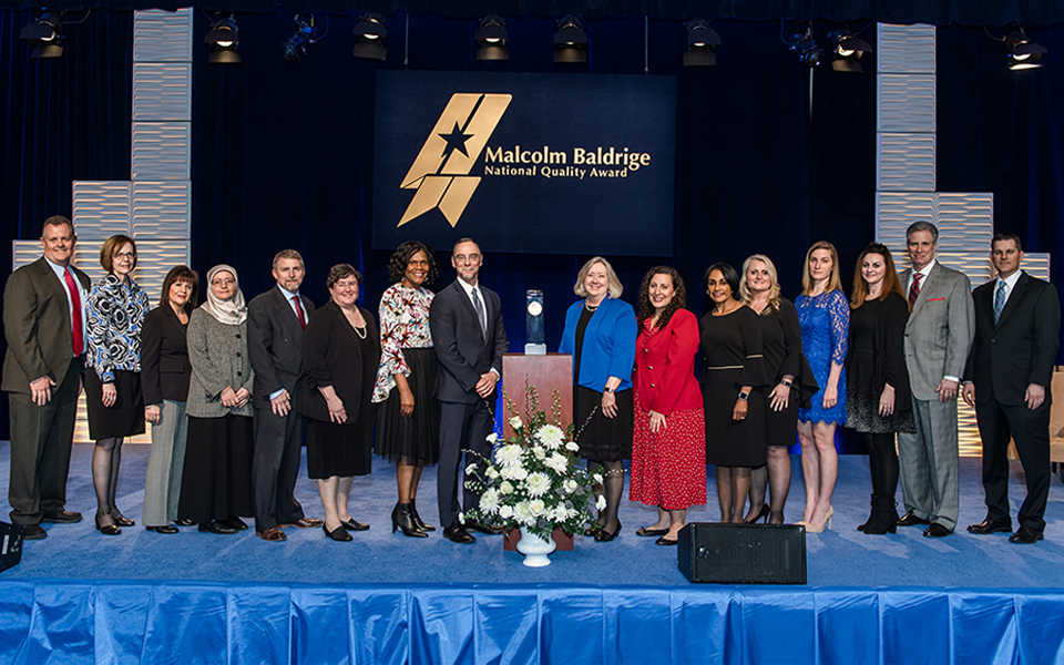 Baldrige staff dressed in formal wear stands for a photo after an awards ceremony.